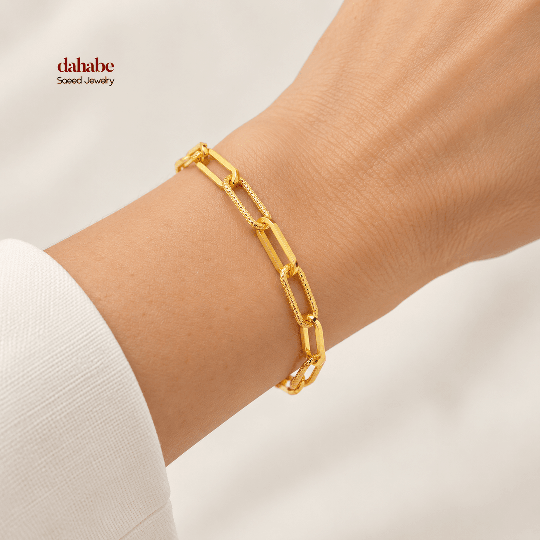 21K yellow gold alternating smooth and textured paperclip bracelet worn on an adult wrist; AI-generated try-on simulation.