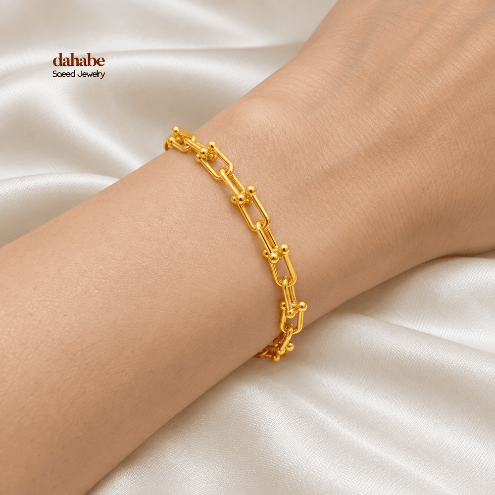 21K yellow gold paperclip bracelet worn on an adult wrist; AI-generated try-on simulation.