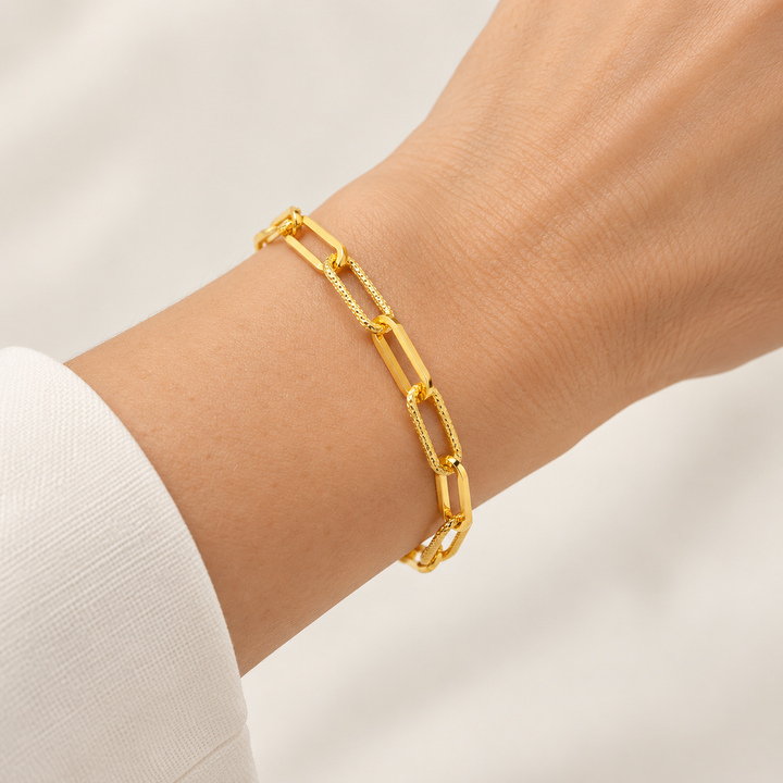 21K yellow gold alternating smooth and textured paperclip bracelet worn on an adult wrist; AI-generated try-on simulation.