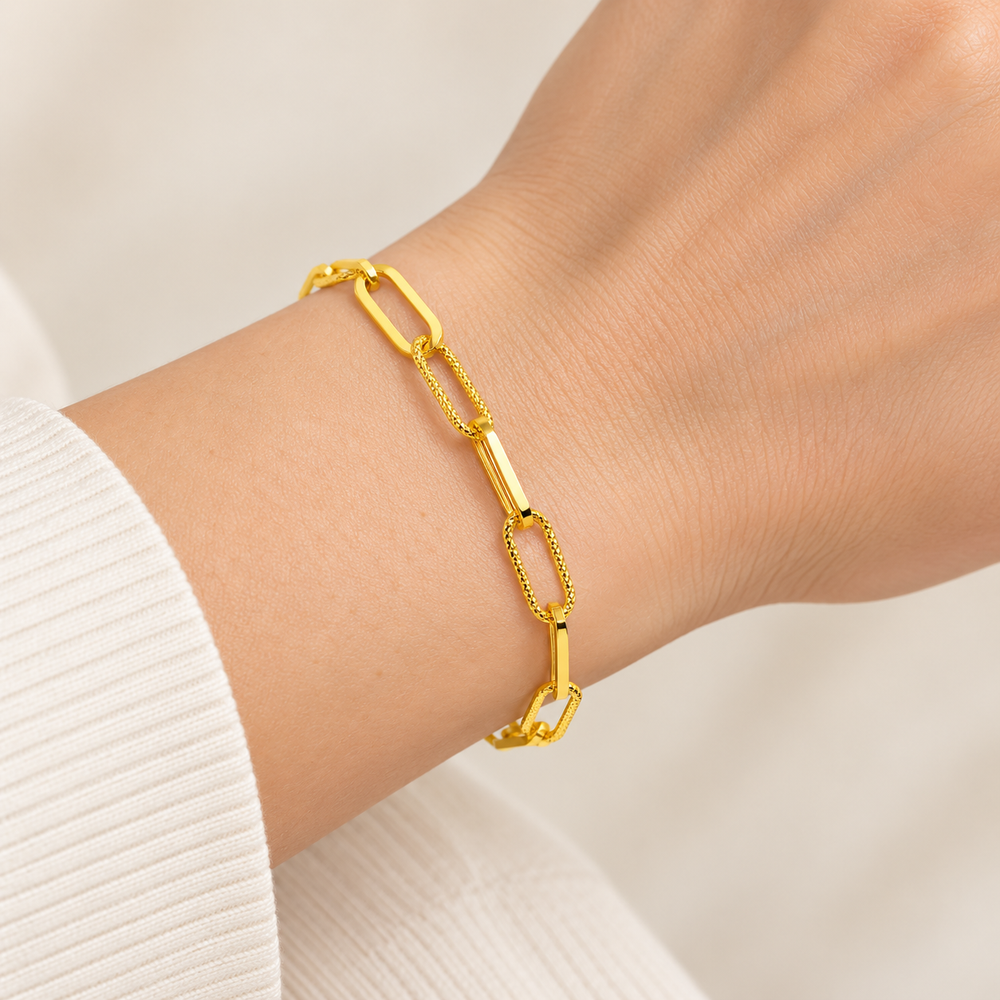 21K yellow gold light paperclip bracelet with alternating textured links and solid bar connectors worn on an adult wrist; AI-generated try-on simulation.