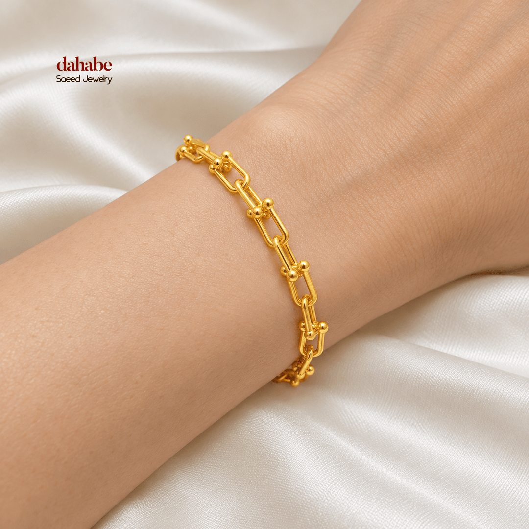 21K yellow gold paperclip bracelet worn on an adult wrist; AI-generated try-on simulation.